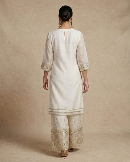 Back view of KISHWAR ivory organza kurta with button-loop keyhole, embroidered sleeve cuffs and double gota hem.