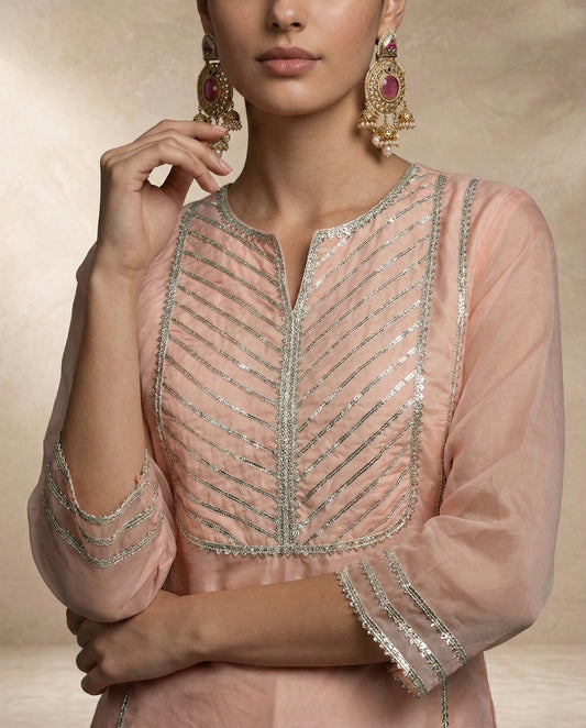 Back view of ZEENAT peach organza kurta with button-loop keyhole and triple gota-line sleeve bands.