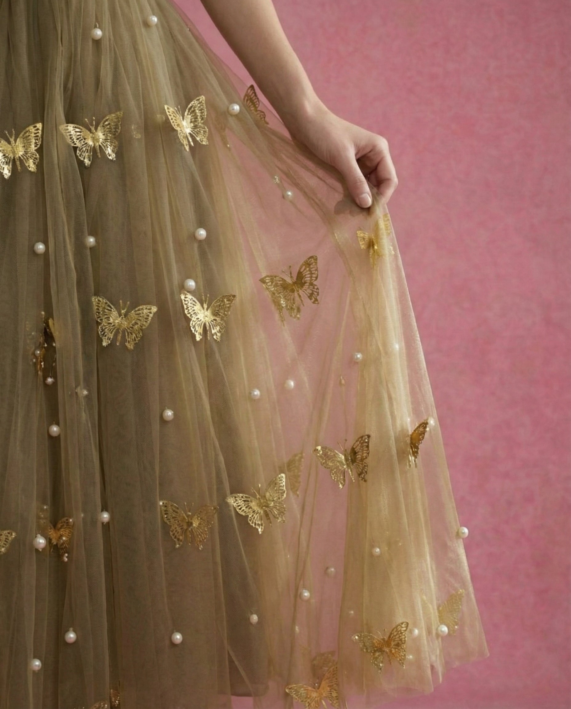 Model wearing SOREN, an ankle-length olive tulle gown with gold metal butterflies and pearls