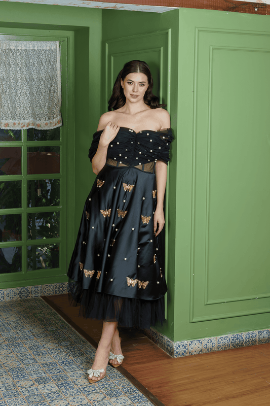 Midnight Siren black dress, front view — off-shoulder tulle drape, pearl-ruched bodice, satin skirt with gold metal butterflies