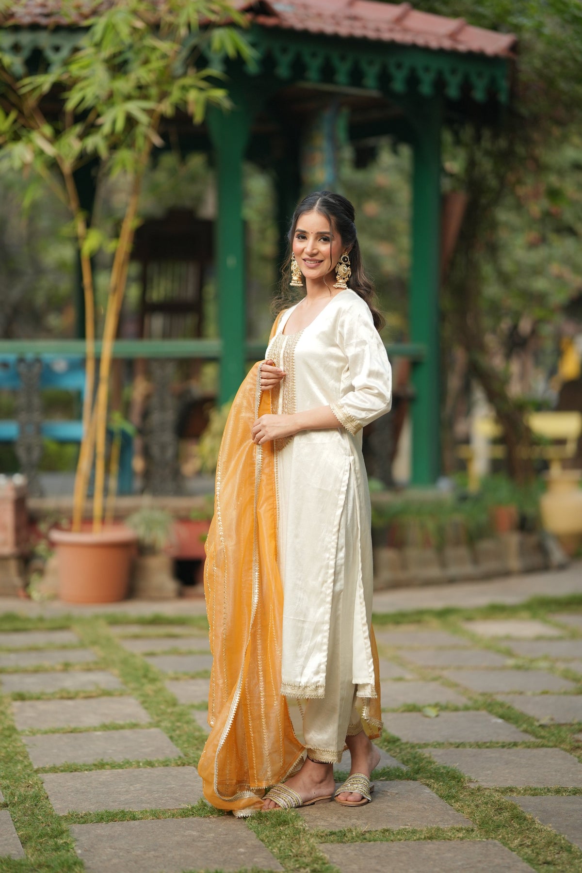 Orange tissue dupatta with diagonal gold embroidery over the off white silk kurta.