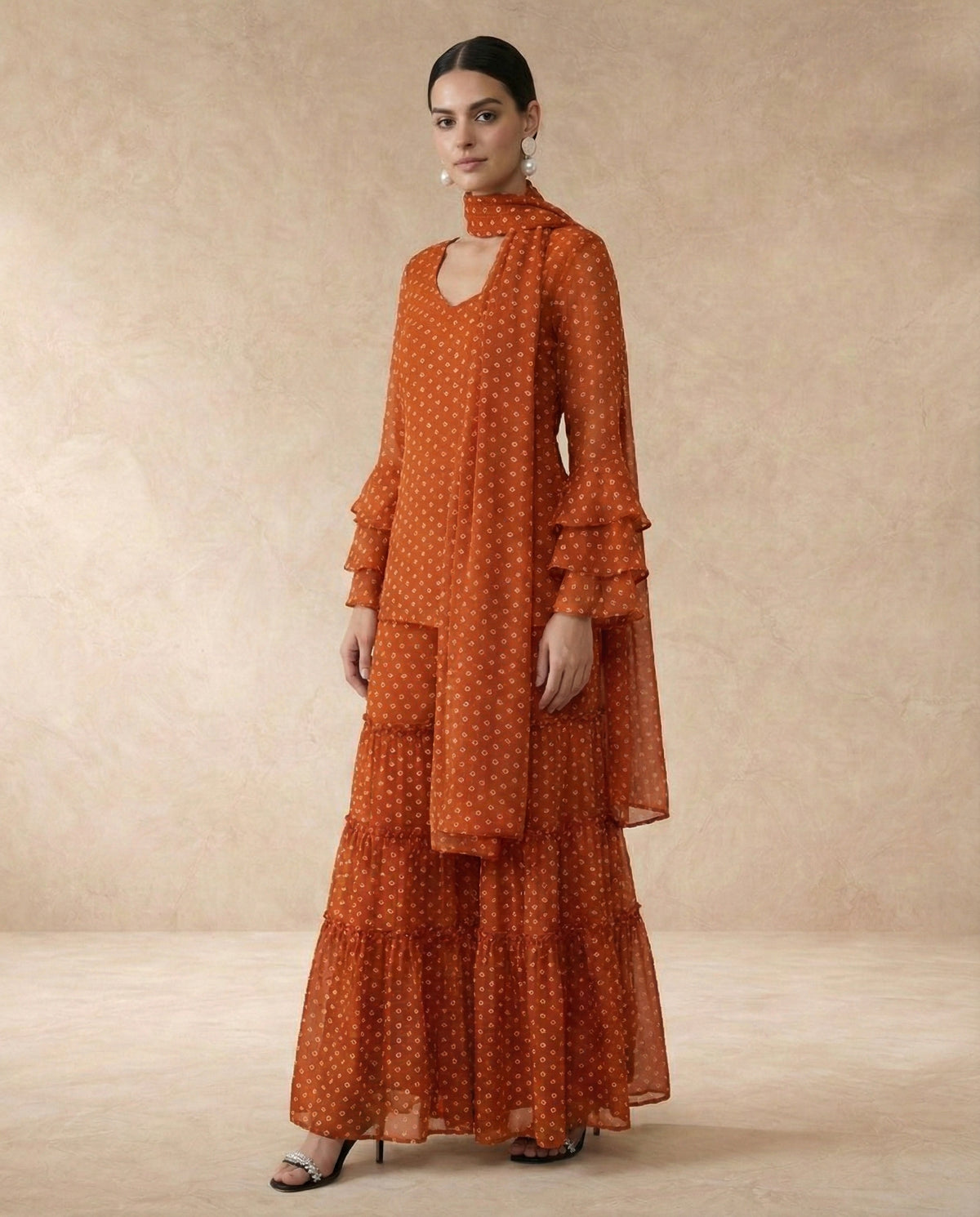 AMBER rust bandhani print georgette sharara set with sweetheart neck and ruffle bell sleeves.