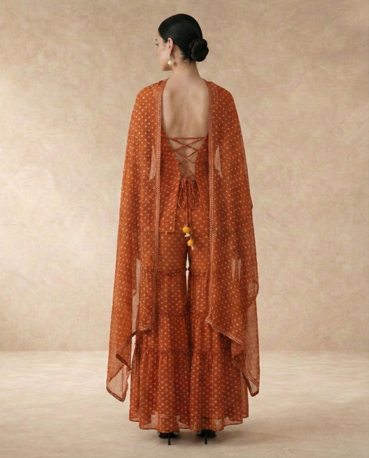 Back view of AMBER rust sharara set with criss-cross lace-up doori back and yellow pom-pom ties.