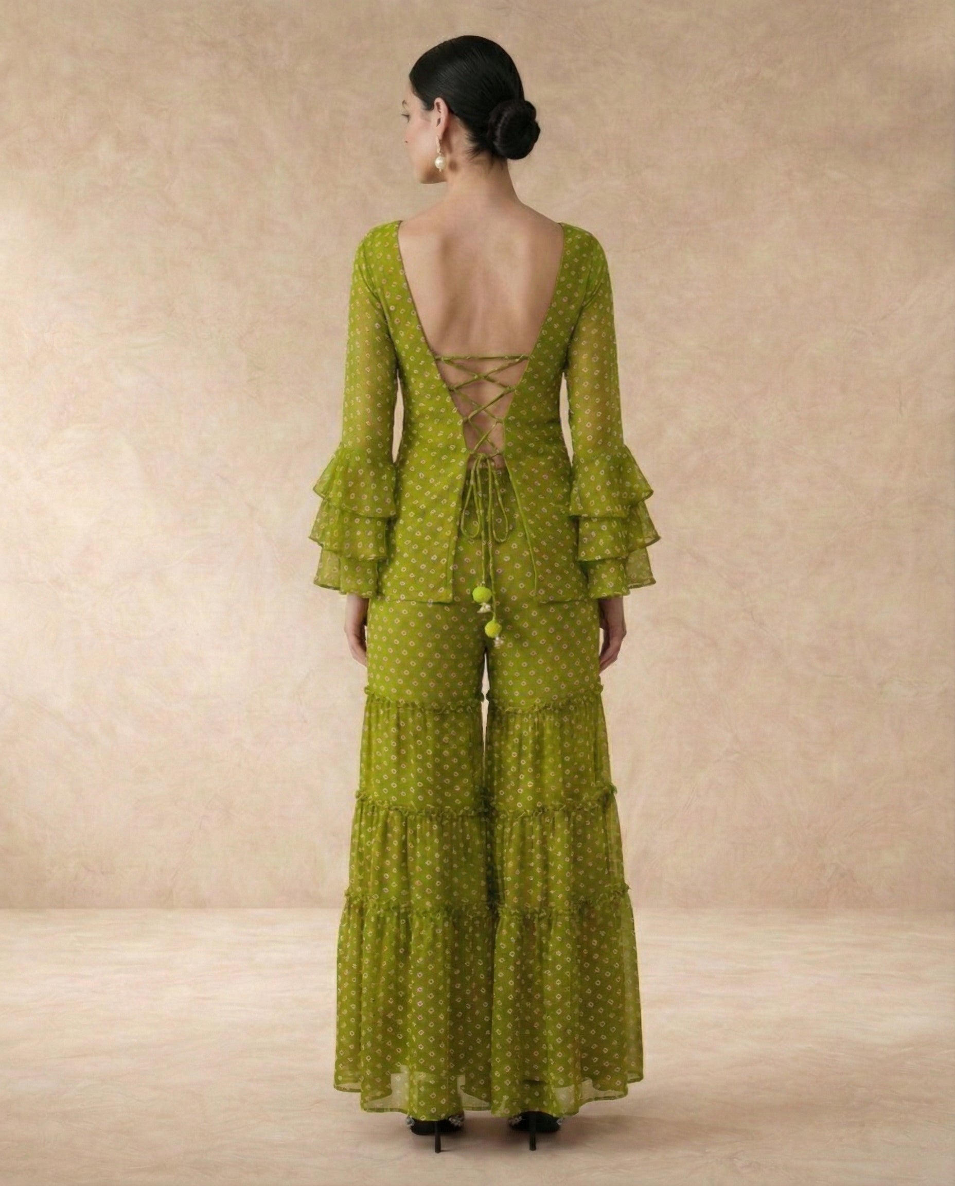 Back view of NAVYA green sharara set with criss-cross lace-up doori back and green pom-pom ties.