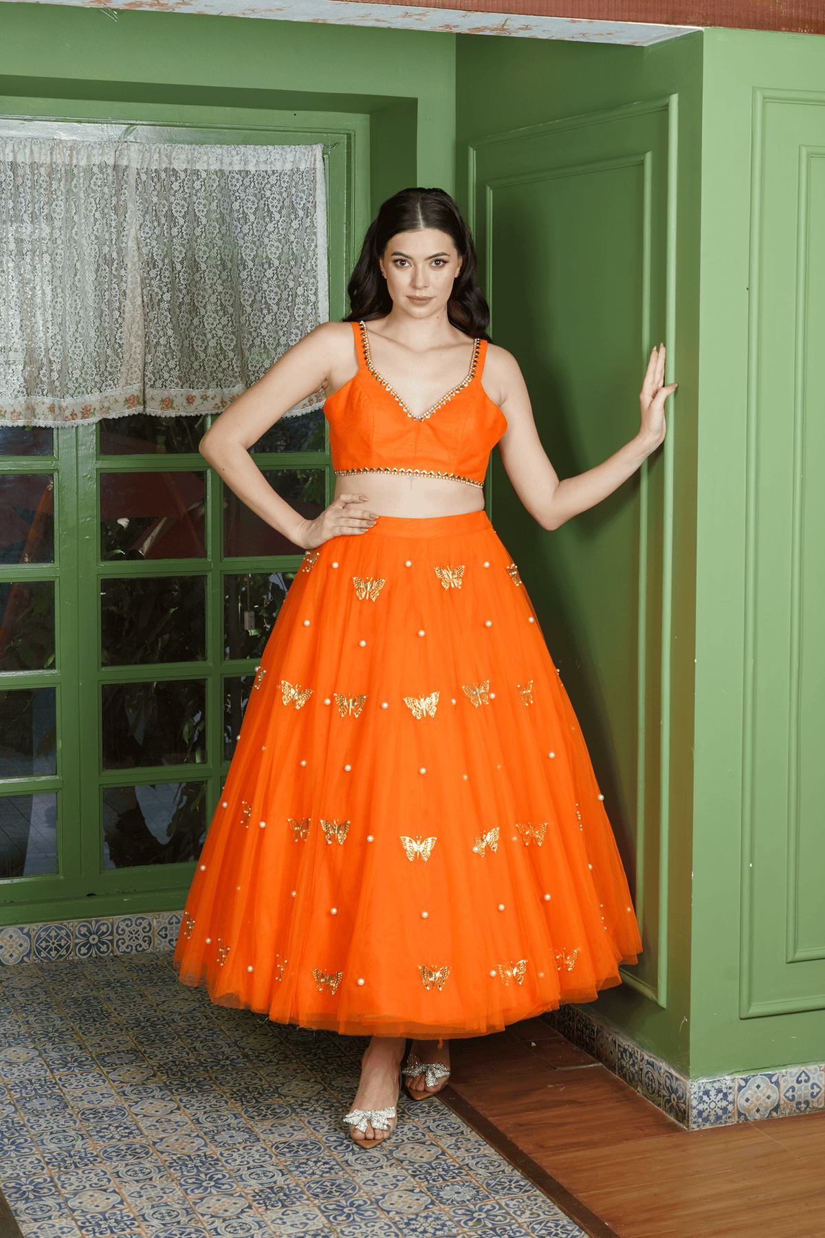 Woman wearing orange lehenga choli with butterfly motifs