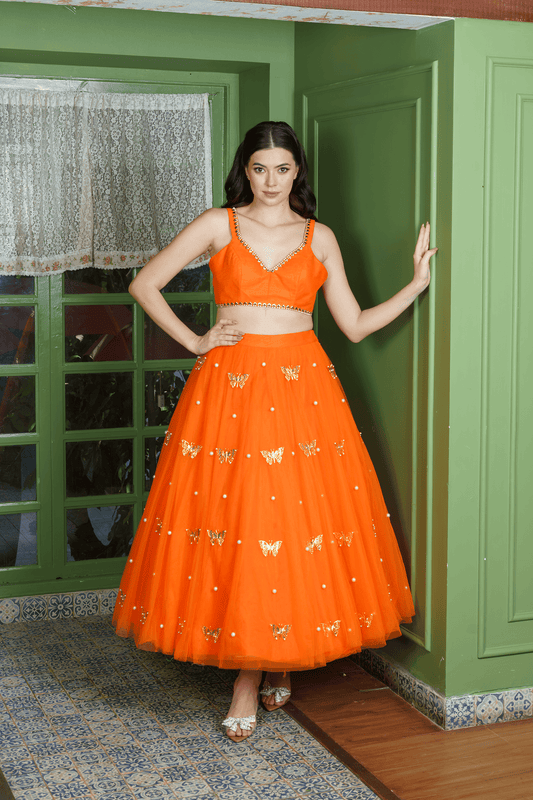 Woman wearing orange lehenga choli with butterfly motifs