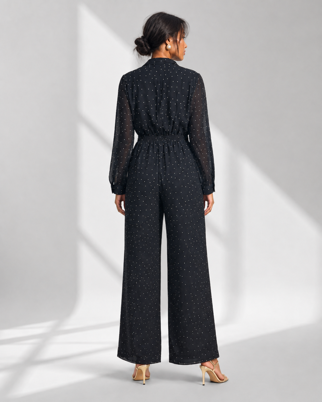 Back view of the SEVERINE navy dot jumpsuit showing sheer sleeves and elasticated waist.