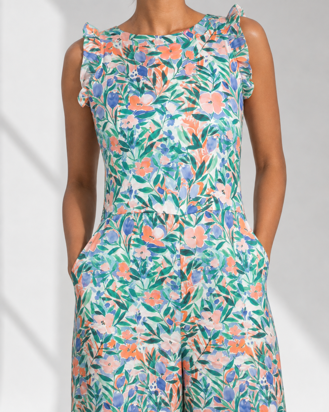 Close view of the watercolour garden floral print and shoulder ruffle on the white FLEUR jumpsuit.