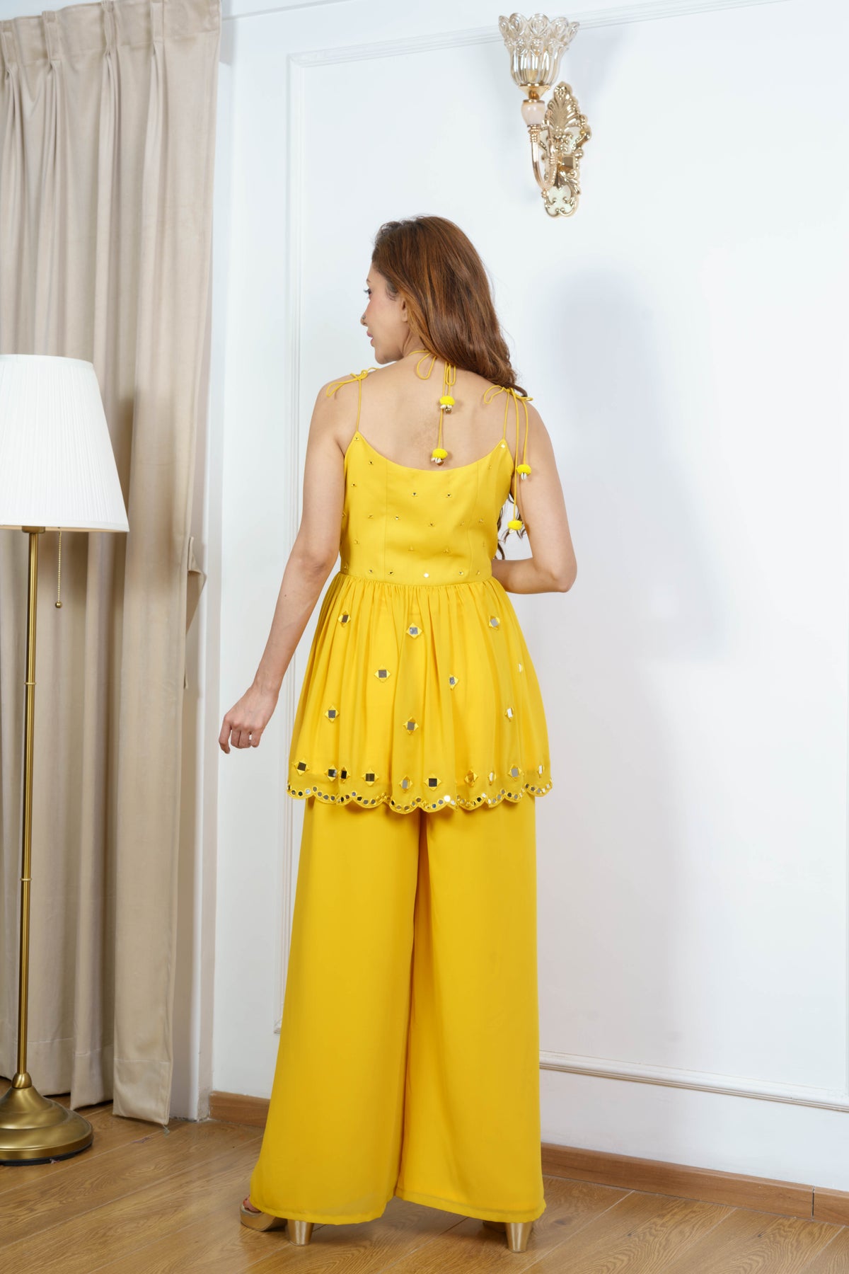 Back view of ZIA flap kurta with doori ties at the shoulder and back, pom-pom tassels and flared sharara.