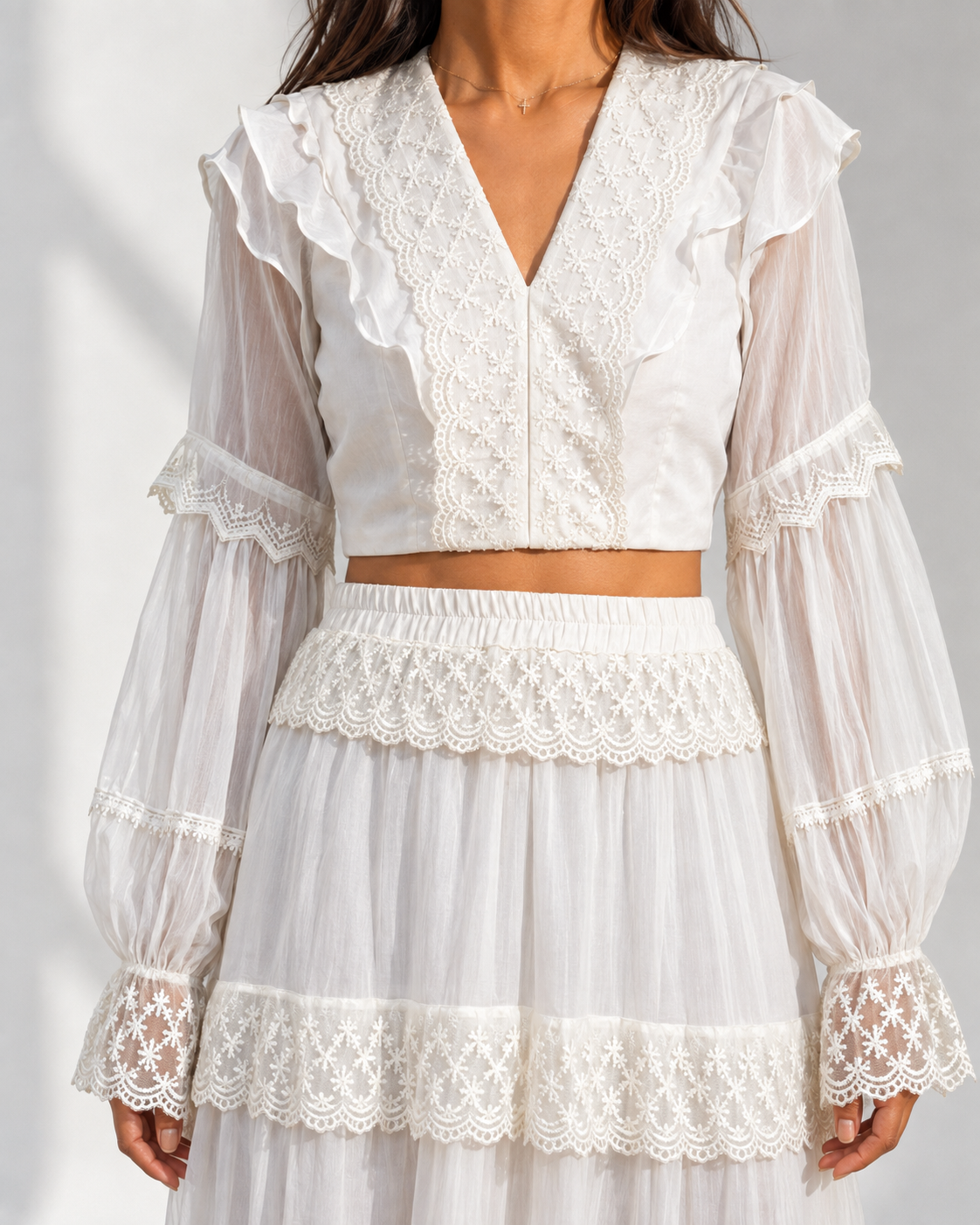 Close view of the lace trims, ruffled shoulders and flounce cuffs on the MORWENNA ivory crop top.